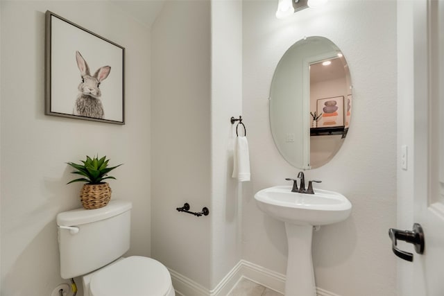 half bathroom featuring toilet, baseboards, and tile patterned floors