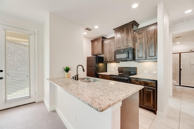 kitchen featuring visible vents, a sink, black appliances, and light stone counters