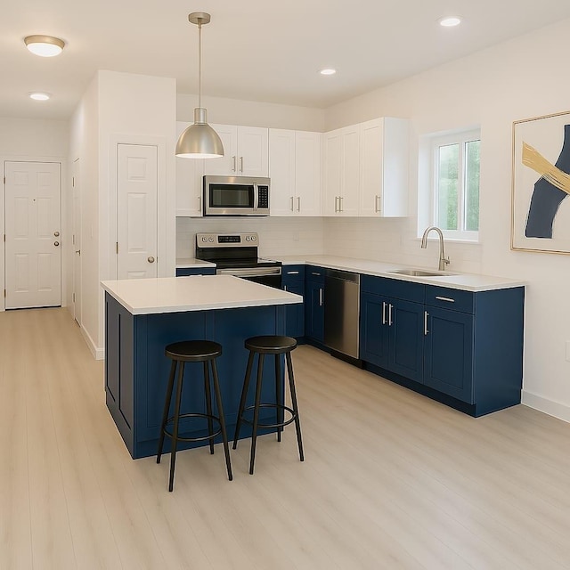 kitchen featuring light wood finished floors, stainless steel appliances, light countertops, blue cabinets, and a sink