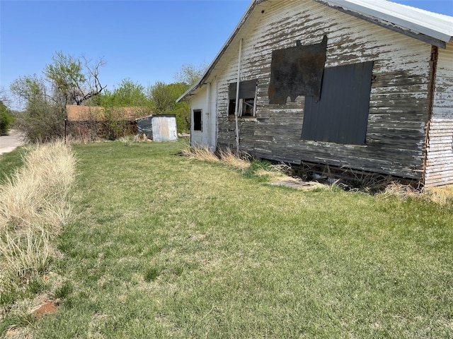 view of side of property featuring a lawn and an outbuilding