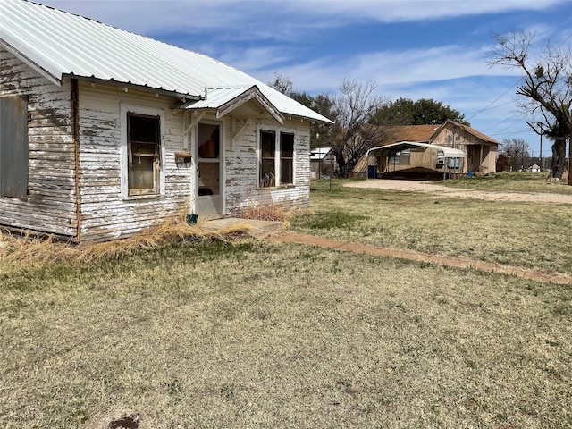 view of front of property with a detached carport, a front lawn, and metal roof