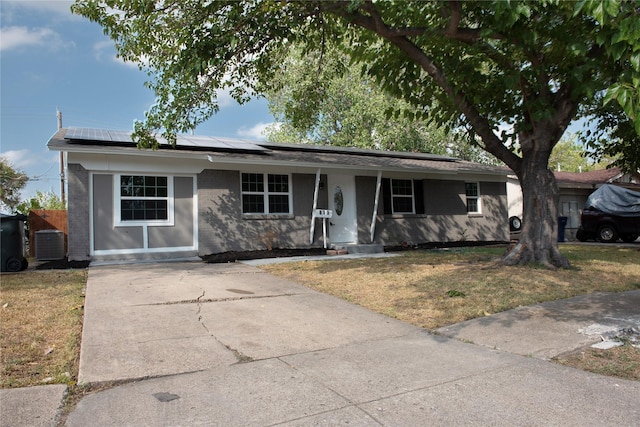 ranch-style house featuring roof mounted solar panels, covered porch, a front yard, and concrete driveway