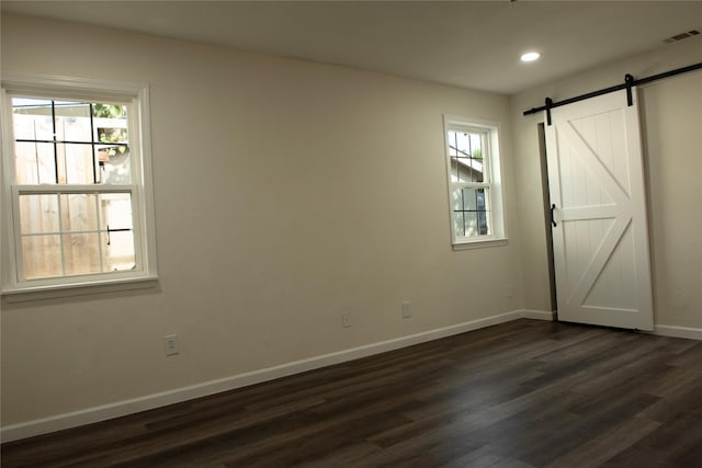 unfurnished bedroom with a barn door, baseboards, dark wood-style flooring, and recessed lighting