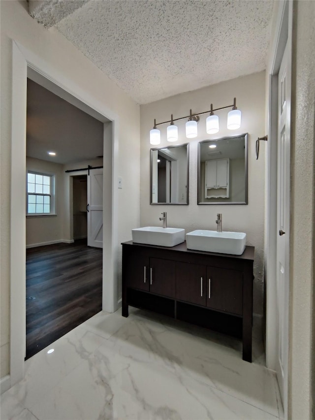 bathroom with a sink, double vanity, and a textured ceiling