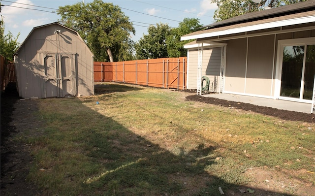 view of yard with a fenced backyard, an outdoor structure, and a storage shed