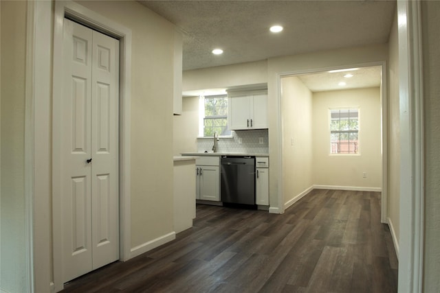 kitchen featuring backsplash, white cabinetry, dishwashing machine, light countertops, and dark wood-type flooring