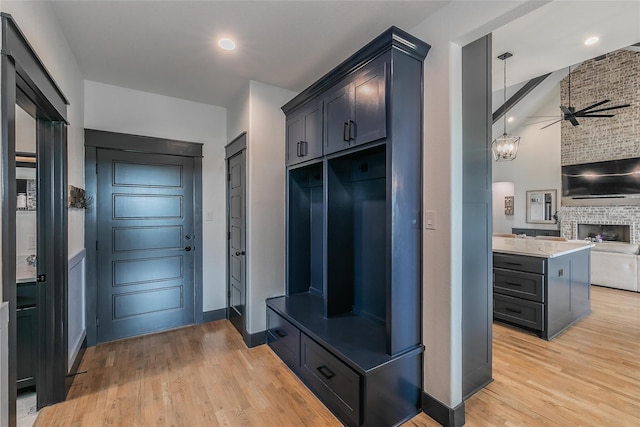 mudroom featuring ceiling fan, baseboards, light wood-style flooring, and a fireplace