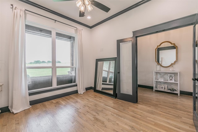 spare room featuring light wood-type flooring, a ceiling fan, and crown molding