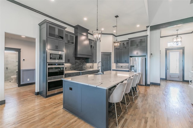 kitchen featuring a sink, an inviting chandelier, custom range hood, and appliances with stainless steel finishes