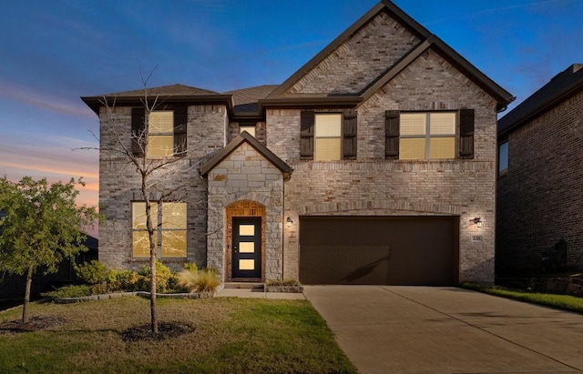 french country home with an attached garage, stone siding, a yard, and concrete driveway