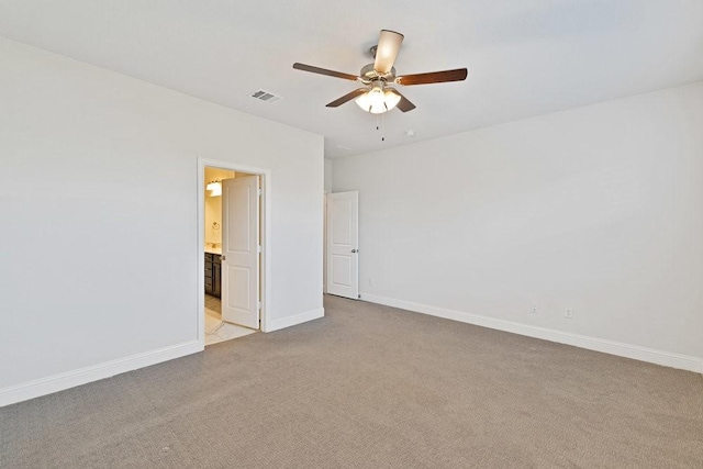 spare room featuring light carpet, a ceiling fan, visible vents, and baseboards