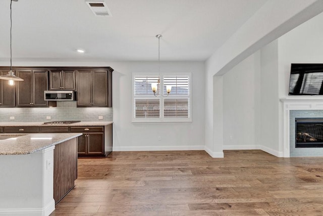 kitchen with light wood-type flooring, visible vents, dark brown cabinetry, and appliances with stainless steel finishes