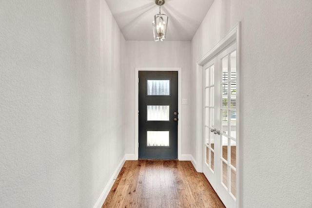 doorway to outside featuring baseboards, hardwood / wood-style flooring, french doors, and a textured wall