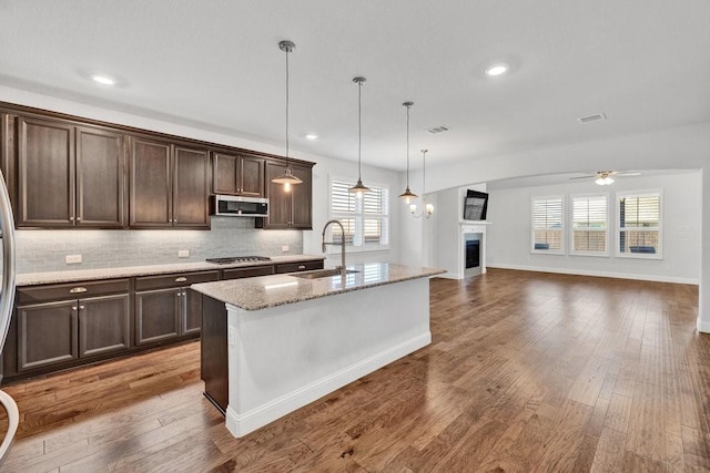 kitchen featuring dark brown cabinets, a sink, ceiling fan, stainless steel appliances, and a fireplace