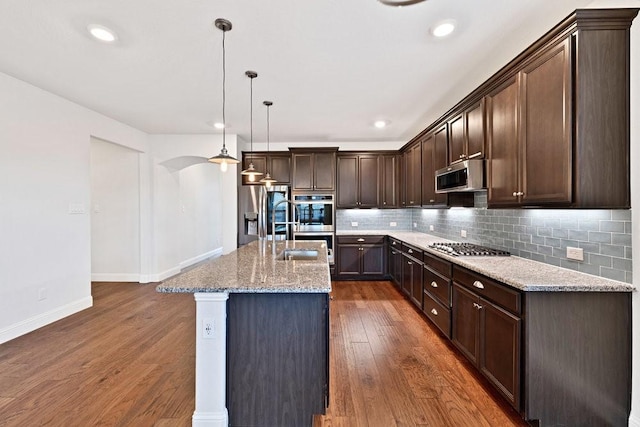 kitchen with stainless steel appliances, dark wood-style flooring, dark brown cabinets, baseboards, and backsplash