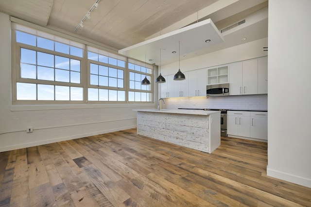kitchen featuring wood finished floors, track lighting, baseboards, appliances with stainless steel finishes, and visible vents