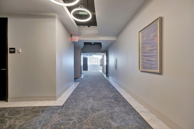 hallway with baseboards and marble finish floor