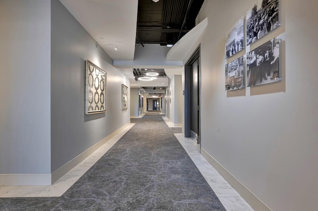 hallway with marble finish floor and baseboards