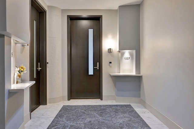 interior space with marble finish floor, baseboards, and elevator