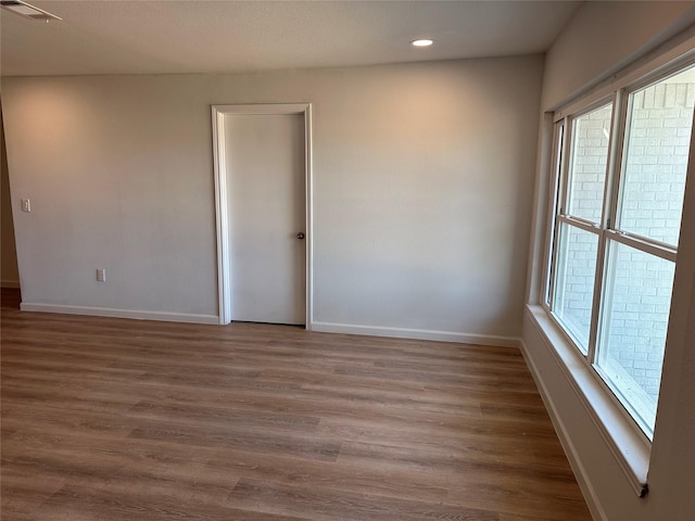 unfurnished room featuring visible vents, baseboards, wood finished floors, and recessed lighting