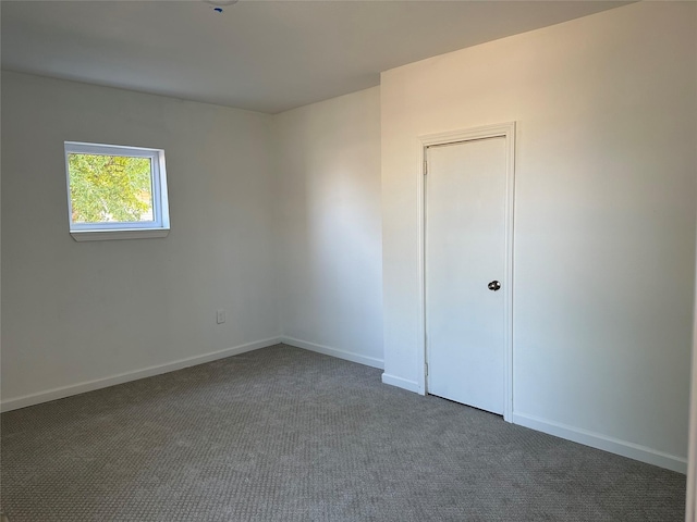 empty room featuring baseboards and dark colored carpet