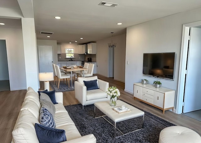 living area with recessed lighting, wood finished floors, visible vents, and baseboards