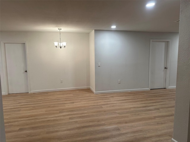 empty room featuring recessed lighting, light wood-style floors, baseboards, and an inviting chandelier