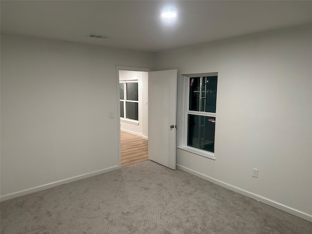 carpeted spare room featuring visible vents and baseboards