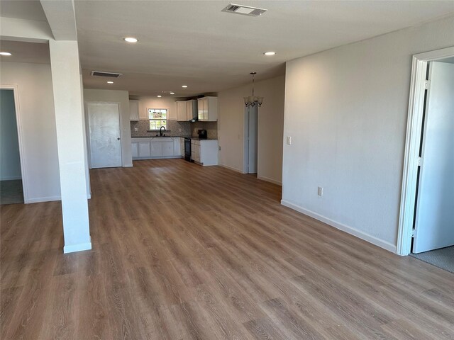 unfurnished living room with baseboards, visible vents, a sink, and recessed lighting
