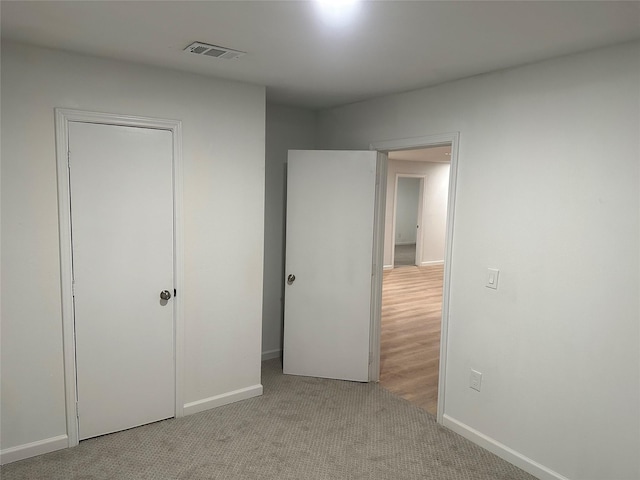 unfurnished bedroom featuring baseboards, carpet flooring, and visible vents