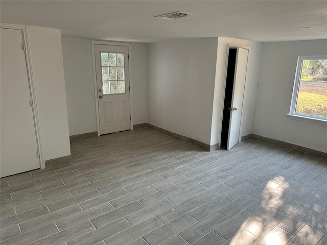 interior space with baseboards, wood finished floors, and visible vents