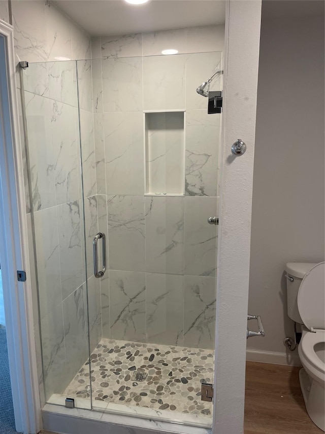 full bath with a shower stall, toilet, baseboards, and wood finished floors