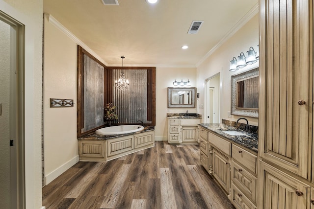 bathroom featuring a garden tub, wood finished floors, a sink, a chandelier, and two vanities