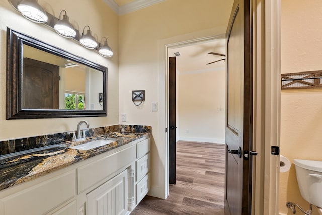 bathroom featuring toilet, wood finished floors, vanity, and crown molding