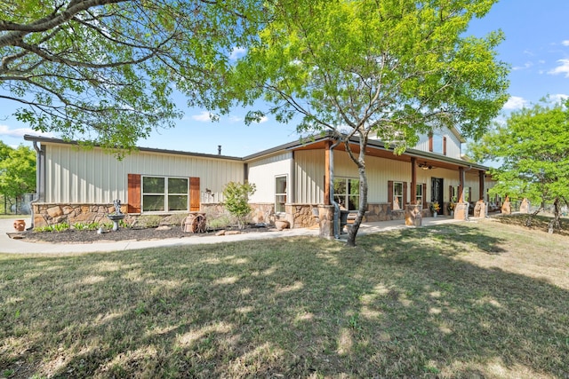 exterior space with a lawn, a patio area, stone siding, and a ceiling fan
