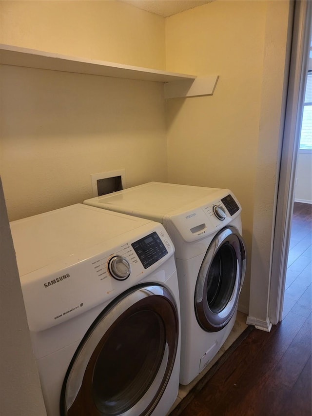 clothes washing area featuring baseboards, laundry area, washer and dryer, and dark wood-style floors