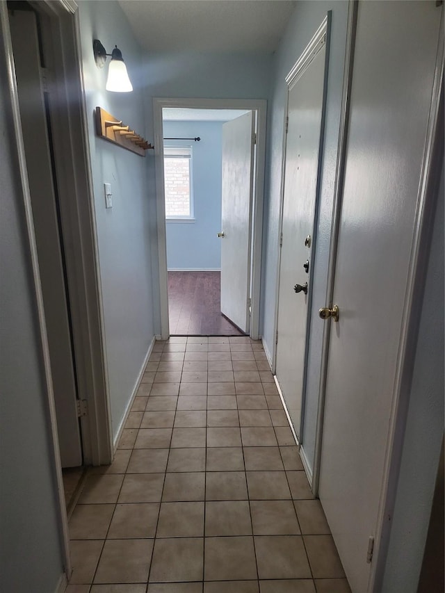 hallway featuring baseboards and light tile patterned floors