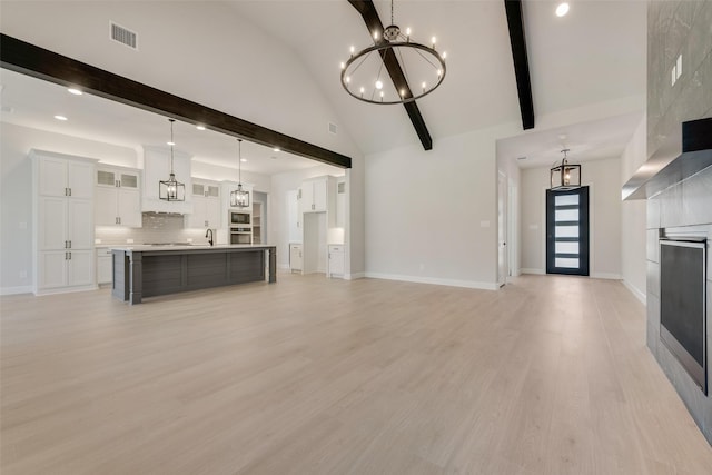 unfurnished living room with baseboards, an inviting chandelier, visible vents, and light wood-type flooring