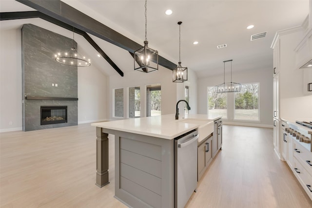 kitchen featuring stainless steel dishwasher, a sink, visible vents, and an inviting chandelier