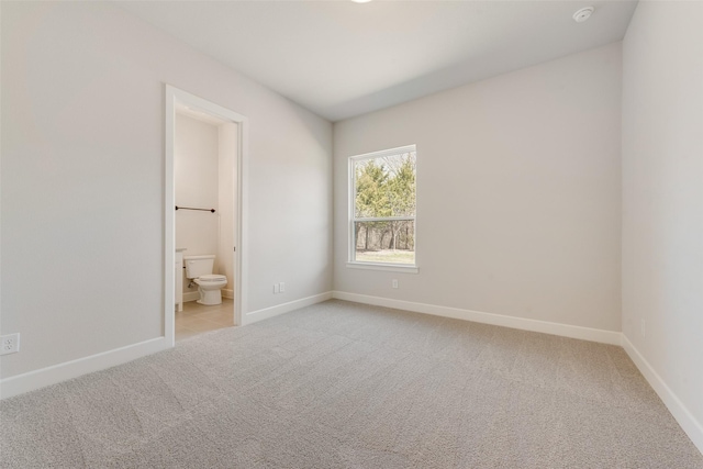 unfurnished bedroom with baseboards, light colored carpet, and connected bathroom