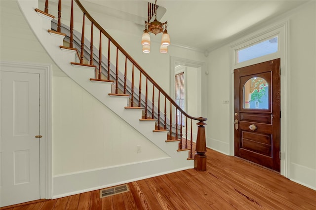 foyer entrance with wood finished floors, visible vents, a notable chandelier, and stairway