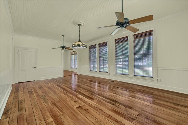 empty room featuring hardwood / wood-style floors, a ceiling fan, a wealth of natural light, and crown molding