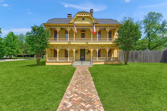 back of house featuring a chimney, a fenced backyard, a yard, driveway, and a patio