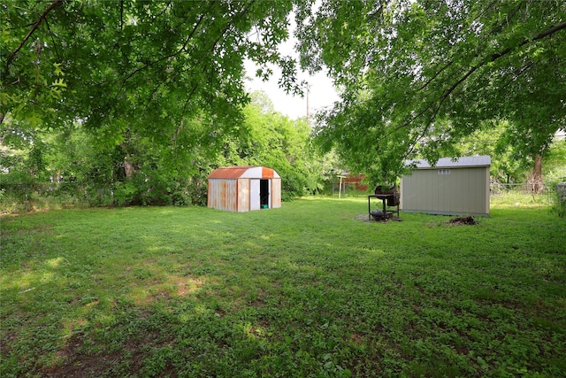 view of yard with fence, an outbuilding, and a shed