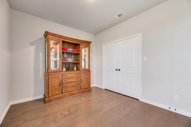 spare room featuring wood finished floors, visible vents, and baseboards