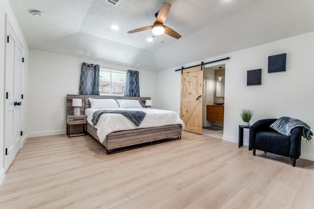 4043 Flintridge Dr, Dallas, TX 75244 - bedroom with a barn door, a raised ceiling, light wood-type flooring, and baseboards