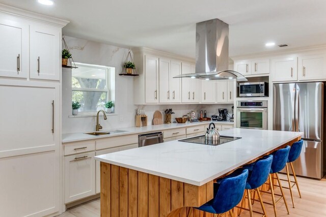 4043 Flintridge Dr, Dallas, TX 75244 - kitchen with stainless steel appliances, island exhaust hood, a sink, a kitchen bar, and a kitchen island