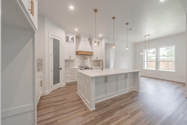 kitchen featuring light wood-type flooring, recessed lighting, white cabinetry, decorative backsplash, and premium range hood