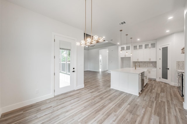 kitchen featuring light wood-type flooring, open floor plan, recessed lighting, decorative backsplash, and light countertops