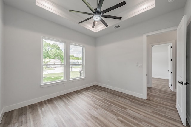 empty room featuring light wood finished floors, ceiling fan, baseboards, and a raised ceiling